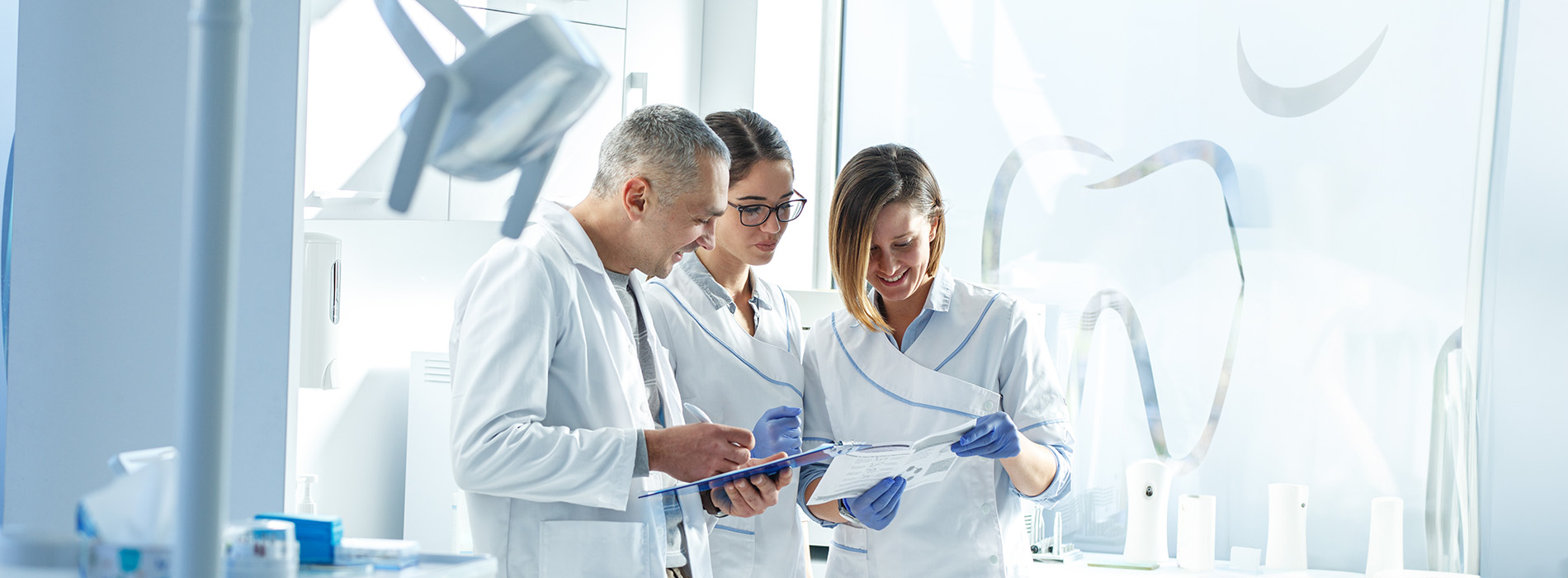 The image shows a group of people in a laboratory setting, with one individual holding a document while others look on.
