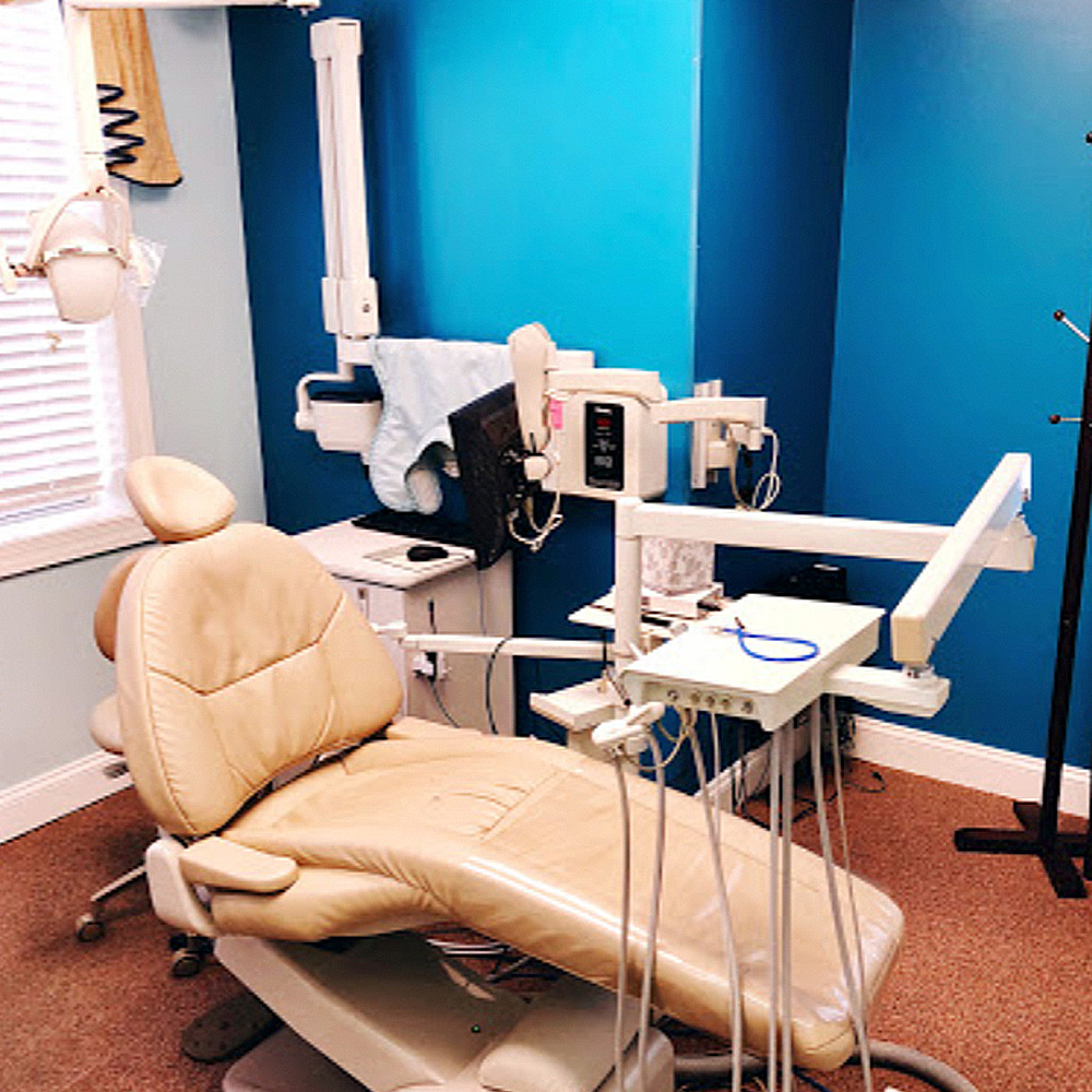 The image shows a dental office interior with a dental chair, a dental light, and various dental equipment.