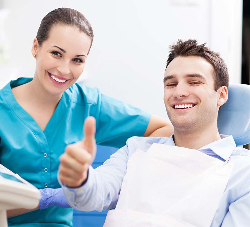 The image shows a dental professional and a patient giving thumbs up in a dental office setting.